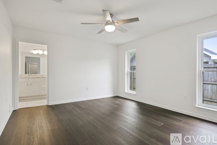 A spacious room with a ceiling fan and hardwood flooring.