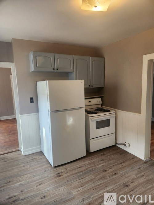 A white refrigerator and stove in a kitchen with wooden floors.