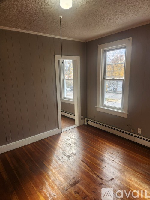 A room with wooden floors and two windows.