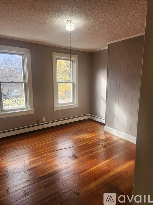 A room with wooden floors and two windows.