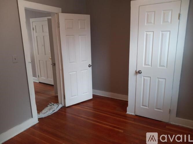 A room with two white doors and a wooden floor.