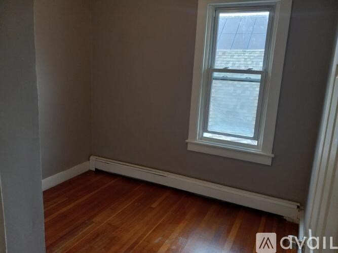 A room with a window and wooden flooring.