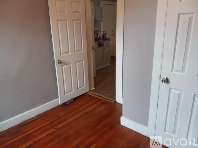 A room with a white door and wooden floors.