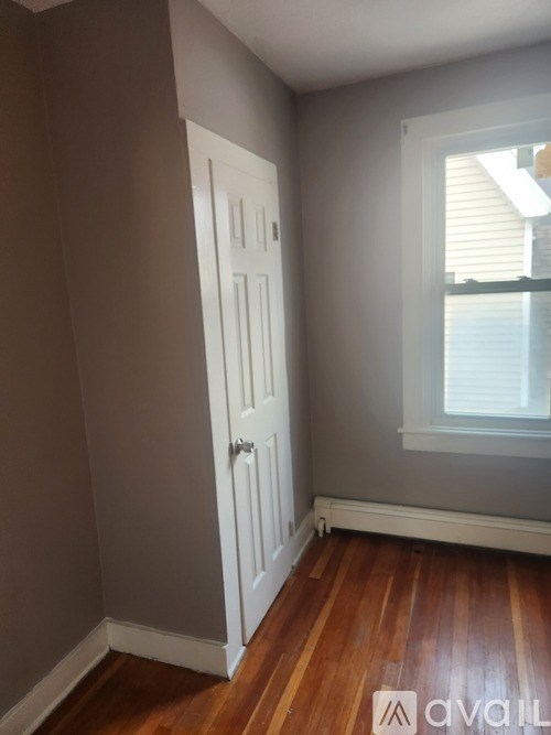 A room with a white door and wooden floors.