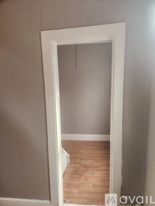 A room with a white door and wooden floor.