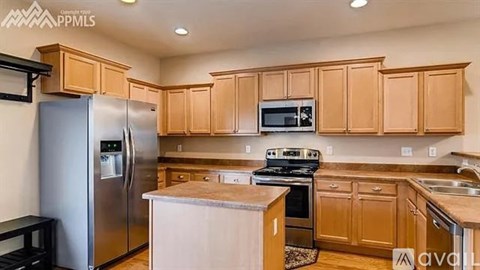 A kitchen with wooden cabinets and a stainless steel refrigerator.