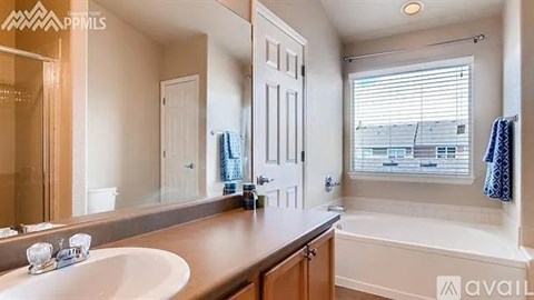 A bathroom with a sink, mirror, and bathtub.