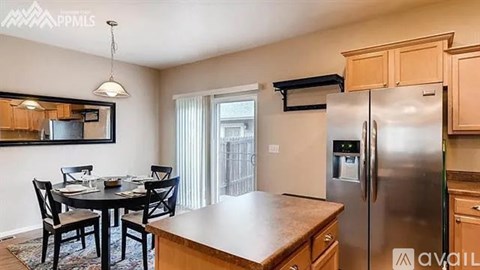 A kitchen with a table and chairs and a fridge.
