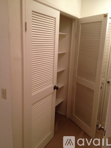 A white closet with a shelf and a door.