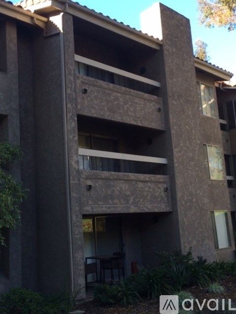 A large concrete building with a balcony and a table and chairs on the balcony.