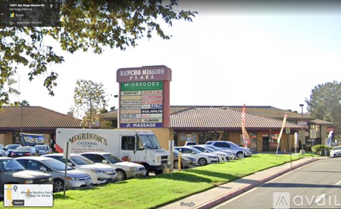 A parking lot with cars and a building with a sign that says Rancho Mission Plaza.