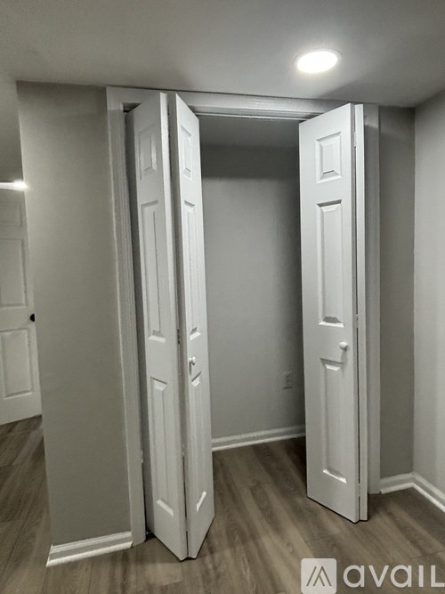 Two white doors in a room with wooden floors.