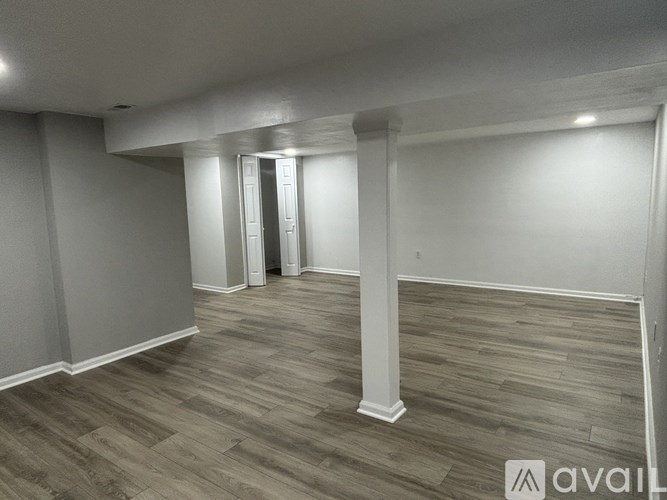 A spacious room with wooden flooring and white columns.