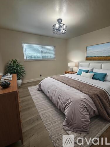A bedroom with a large bed and a painting on the wall.