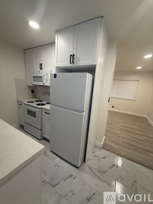 A kitchen with a white fridge, microwave, and oven.