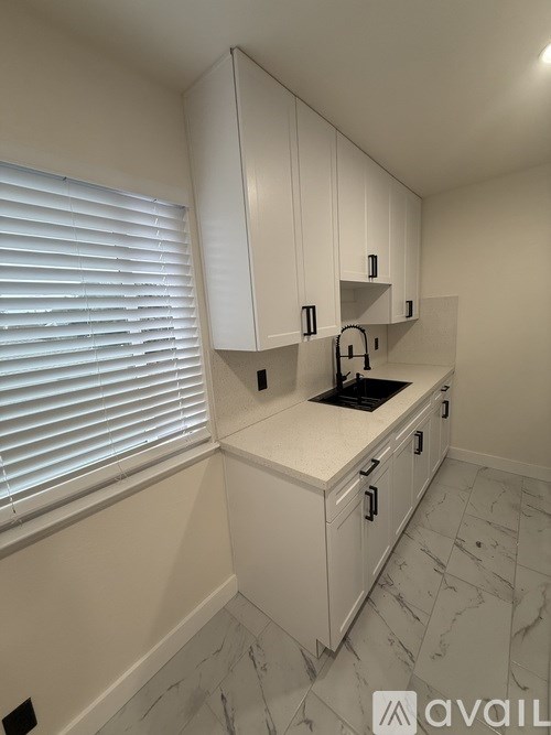A kitchen with white cabinets and a marble floor.