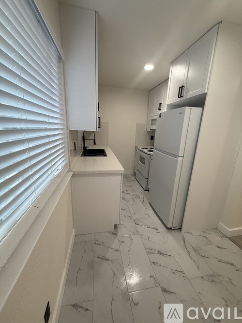 A kitchen with white cabinets and a marble floor.