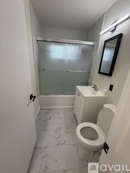 A small bathroom with a toilet, sink and shower.