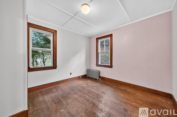 A room with wooden floors and two windows.