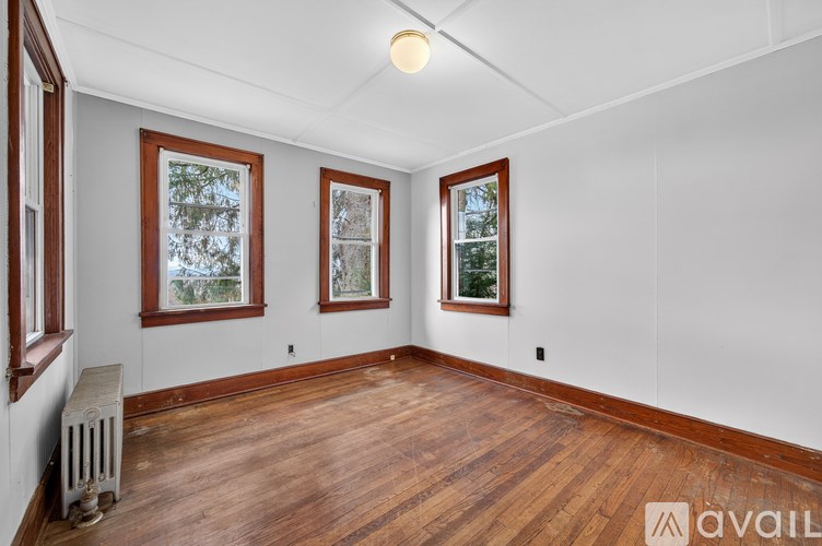 A room with wooden floors and three windows.