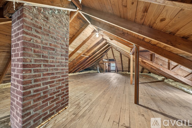 A wooden attic with a brick chimney and wooden beams.