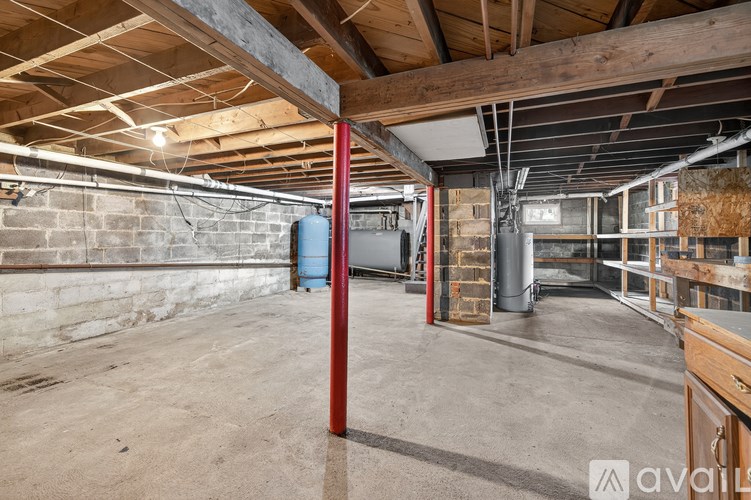 A large empty room with wooden beams on the ceiling and a red pole in the middle.