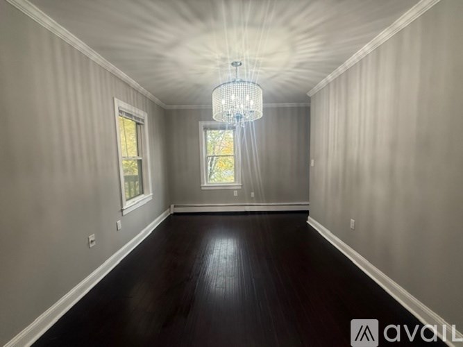 A spacious room with wooden floors and a chandelier.