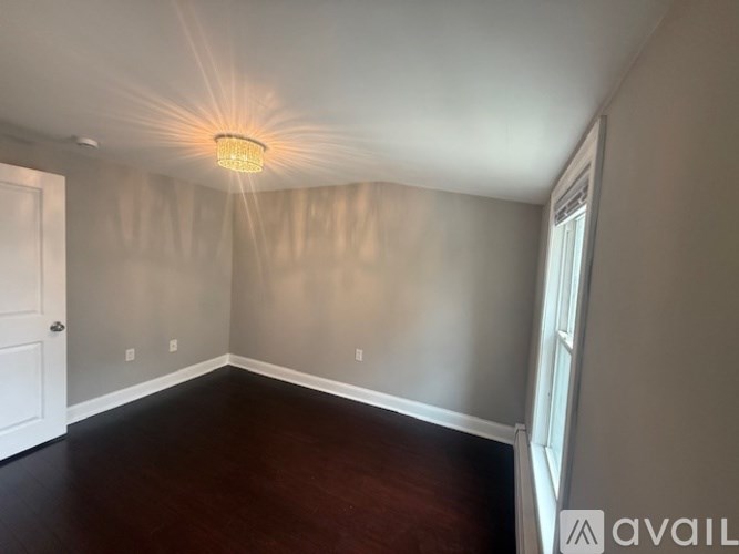 A room with a light on the ceiling and a door on the left.