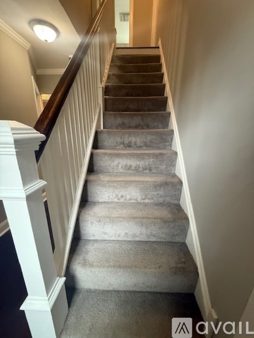 A staircase with a carpeted runner and white balusters.