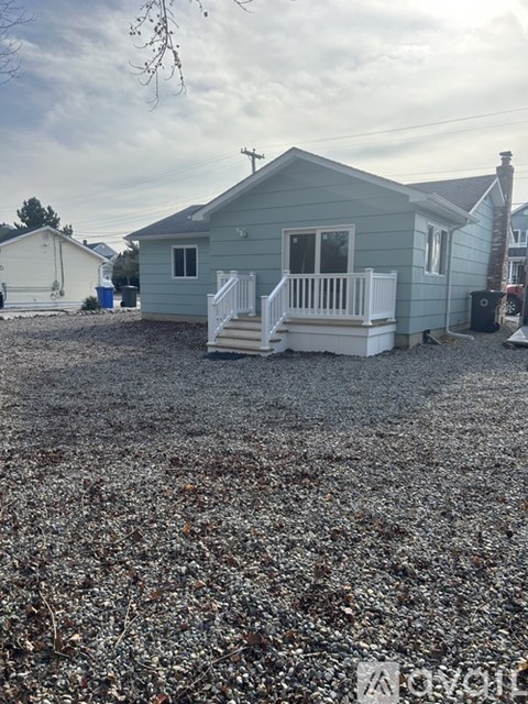 A house with a porch and a gravel yard.