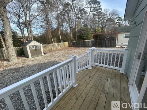 A deck with a white railing and a shed in the background.