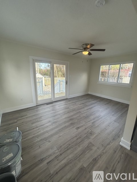 A room with a ceiling fan and sliding glass doors leading to a backyard.