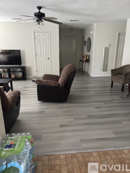 A living room with a television, two chairs, and a box on the floor.