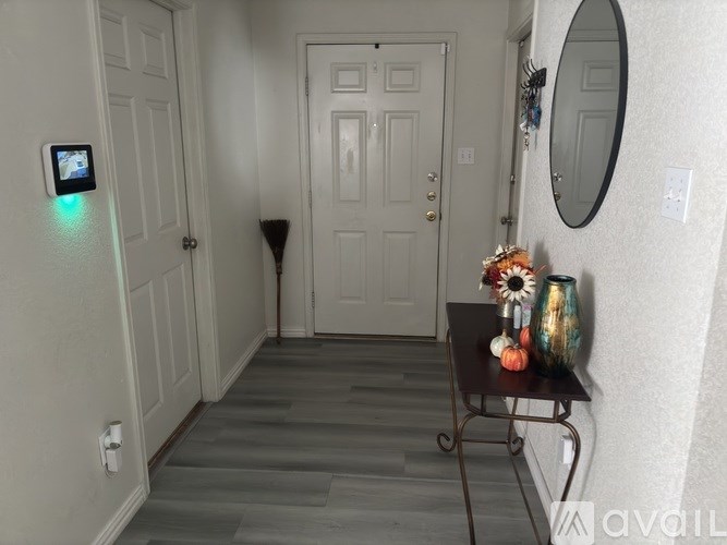 A hallway with a table holding vases and a mirror on the wall.