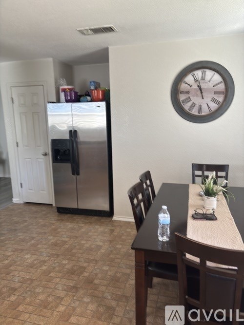 A kitchen with a fridge, table and chairs.