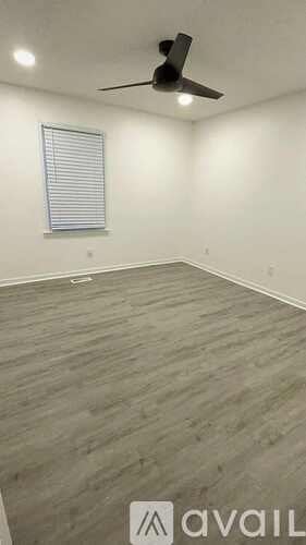 A room with a fan and a window with blinds.