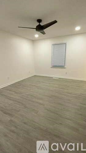 A room with a ceiling fan and a window with blinds.