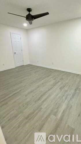 A room with a ceiling fan and wooden flooring.