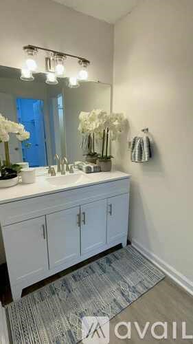 A bathroom with a vanity, mirror, and a strip of lights above it.