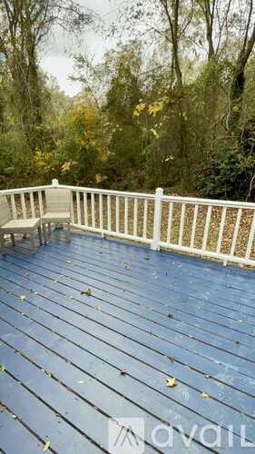A deck with a white railing and fallen leaves on it.