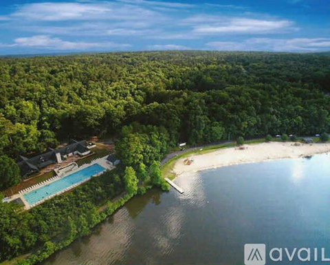 A bird's eye view of a house surrounded by a forest and a beach.