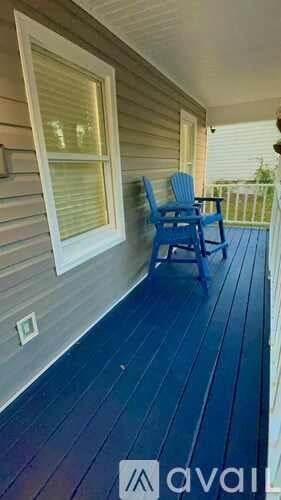 A blue chair is on a porch with a white window.