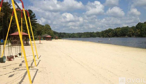A playground with swings is situated on a sandy beach.