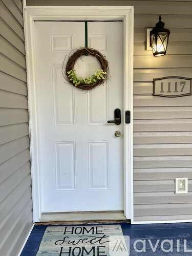 A white door with a wreath and a sign that says "Home Sweet Home".