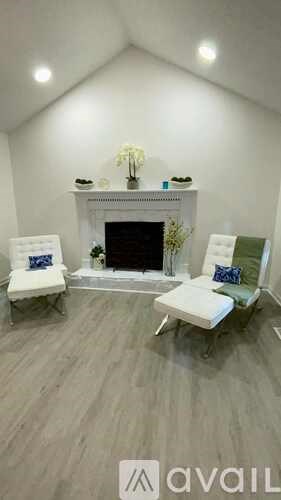 A living room with a fireplace and two chairs.