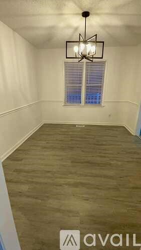 A room with a chandelier and a window with blinds.