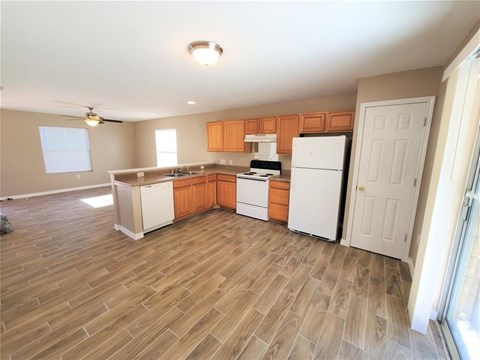 A kitchen with wooden floors and white appliances.