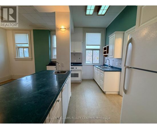A kitchen with a black countertop and white appliances.