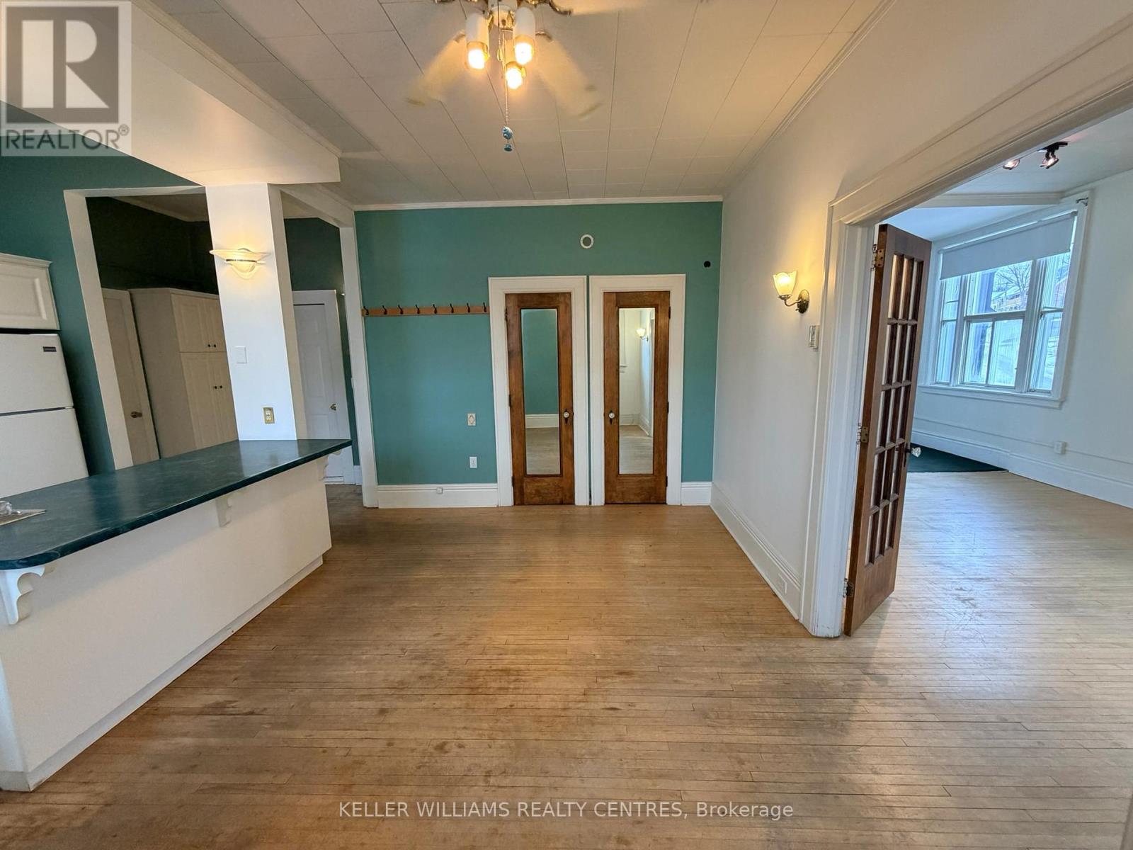 A spacious room with wooden floors and a large window.