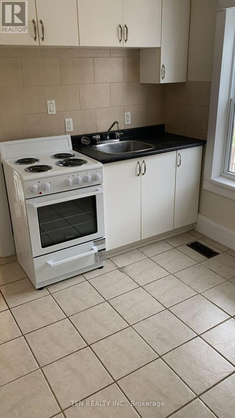 A white stove in a kitchen with beige tiles.